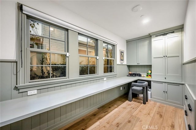 home office with built in desk and light wood-type flooring