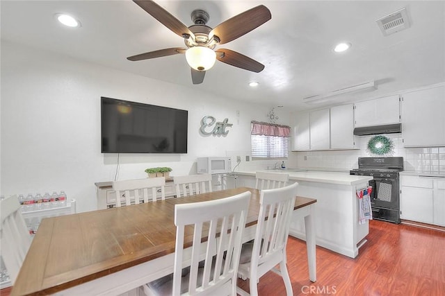 kitchen with tasteful backsplash, wood-type flooring, white cabinetry, sink, and gas stove