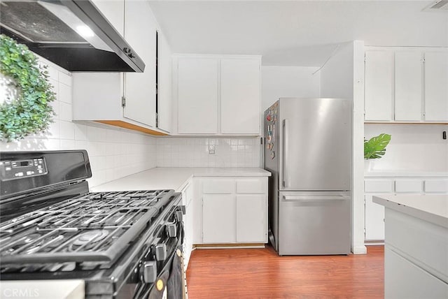 kitchen with white cabinetry, stainless steel refrigerator, and black gas stove