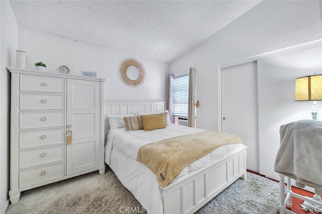 bedroom with lofted ceiling, light colored carpet, a closet, and a textured ceiling