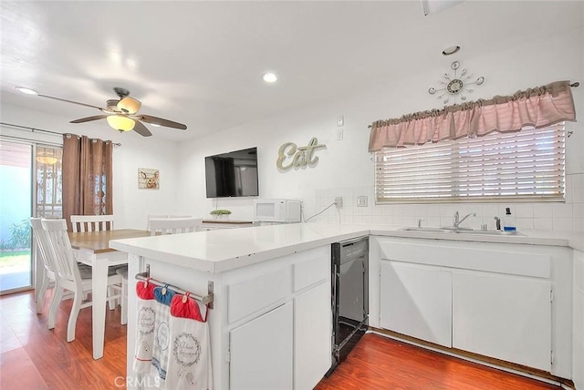 kitchen with sink, kitchen peninsula, dishwasher, decorative backsplash, and white cabinets