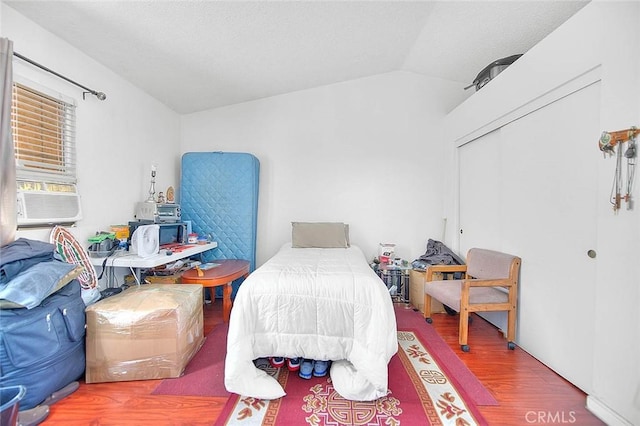 bedroom featuring a closet, lofted ceiling, hardwood / wood-style floors, and cooling unit