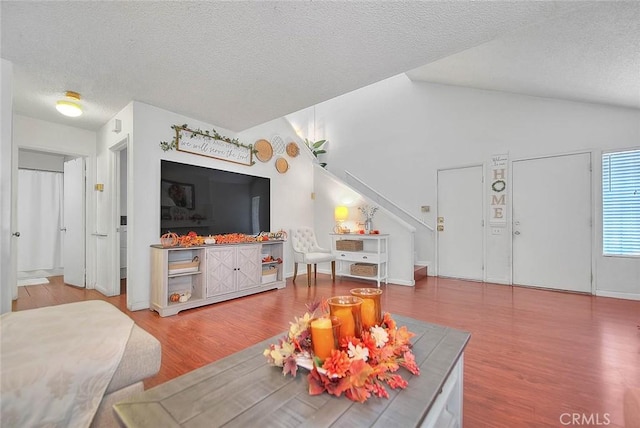 living room with vaulted ceiling, hardwood / wood-style floors, and a textured ceiling