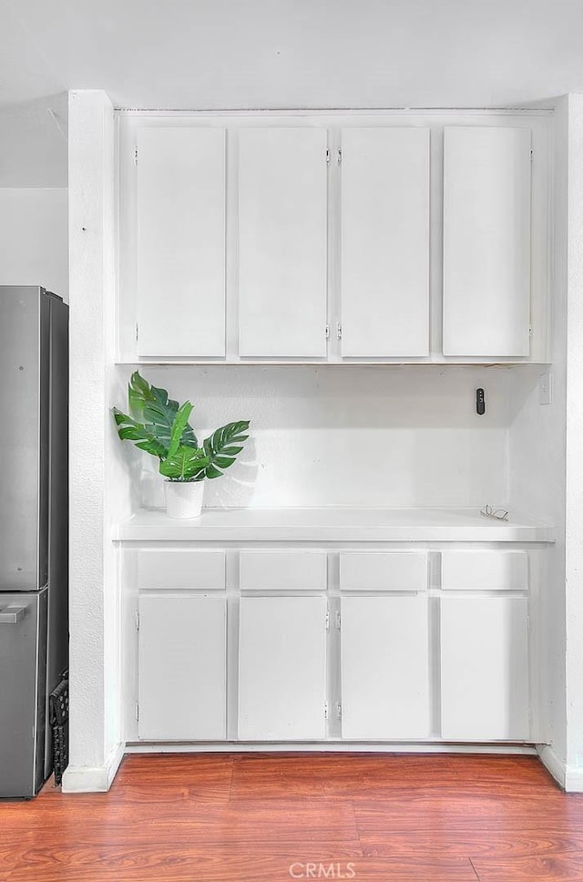 details with stainless steel fridge and hardwood / wood-style floors