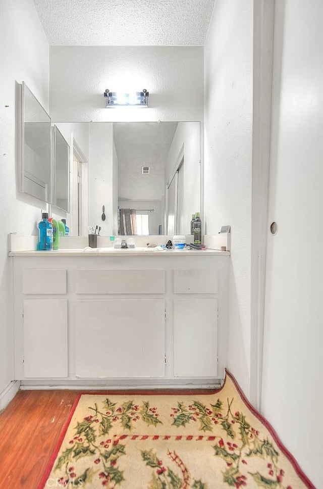 bathroom with wood-type flooring, vanity, and a textured ceiling