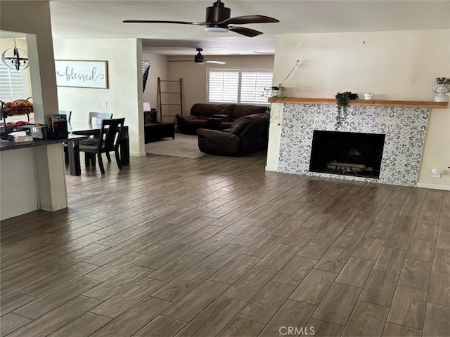 living room with a tile fireplace and ceiling fan