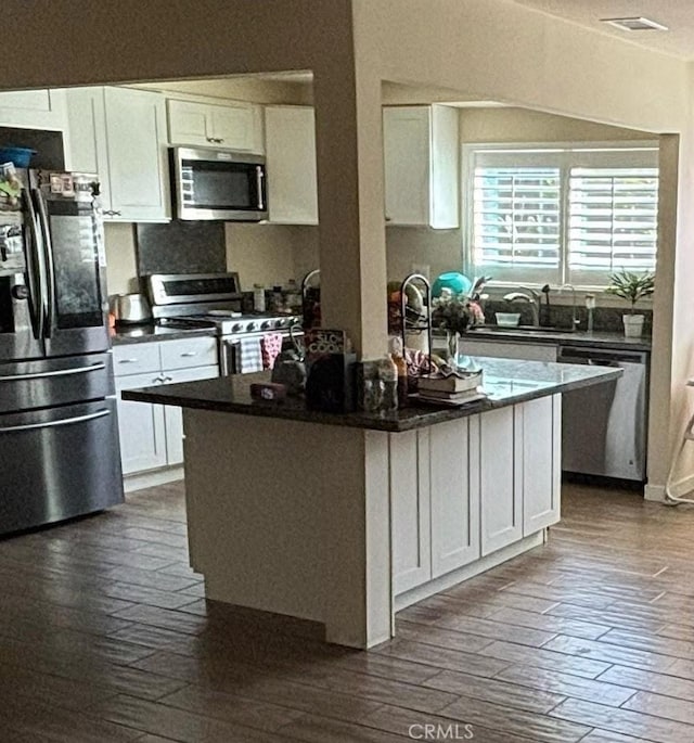 kitchen with an island with sink, white cabinets, and stainless steel appliances