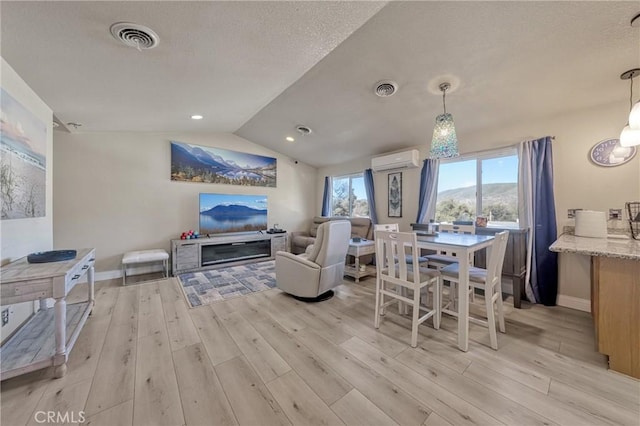 living room with lofted ceiling, light hardwood / wood-style floors, and a wall unit AC