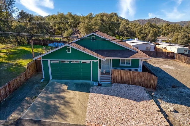 view of front of house with a porch, an attached garage, a mountain view, fence, and driveway