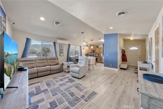 living room featuring vaulted ceiling, a wall mounted air conditioner, and light wood-type flooring