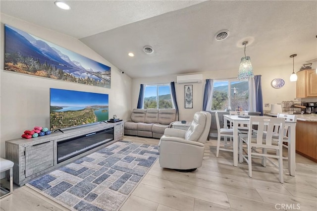 living room featuring vaulted ceiling, a wall unit AC, and light hardwood / wood-style floors