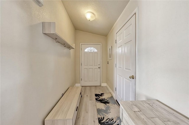 doorway featuring vaulted ceiling and light wood-type flooring