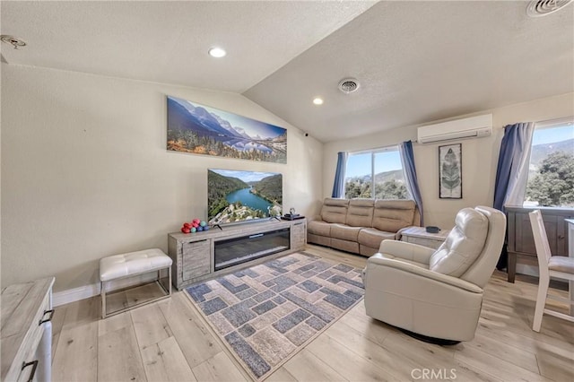 living room with lofted ceiling, a healthy amount of sunlight, a wall mounted air conditioner, and light hardwood / wood-style floors