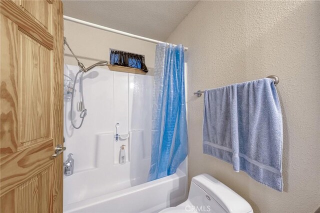 bathroom featuring shower / tub combo with curtain, toilet, and a textured ceiling