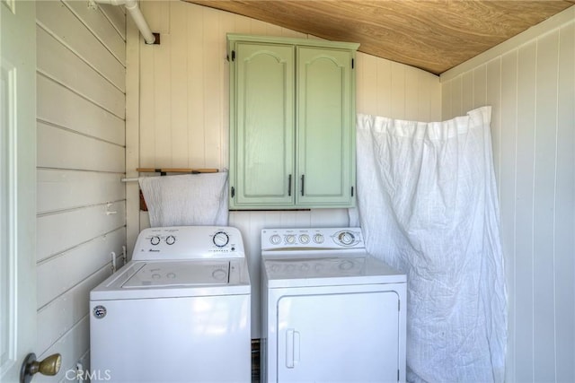 laundry room featuring cabinets, wooden walls, and washer and dryer