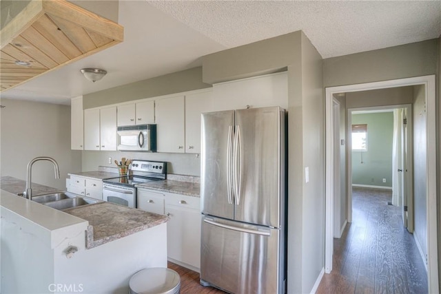 kitchen with white cabinetry, appliances with stainless steel finishes, dark hardwood / wood-style floors, and sink