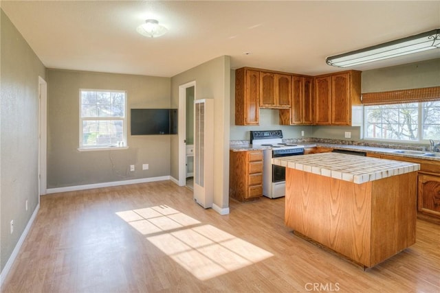 kitchen with sink, light wood-type flooring, tile counters, a kitchen island, and white range with electric cooktop