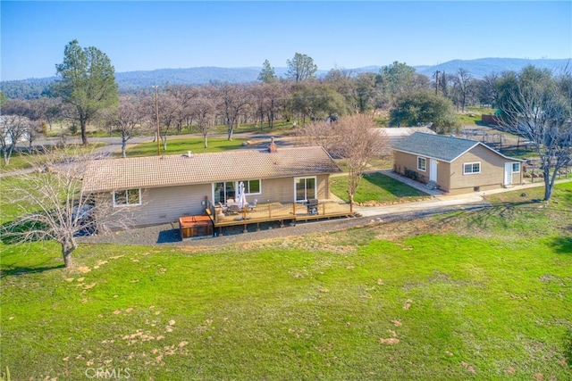 rear view of house with a deck with mountain view and a lawn