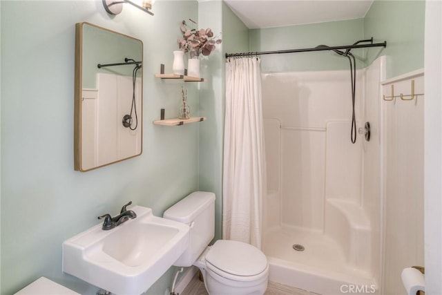 bathroom with a shower with shower curtain, toilet, and sink