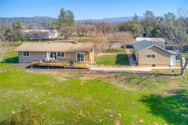 back of property with a yard and a deck with mountain view