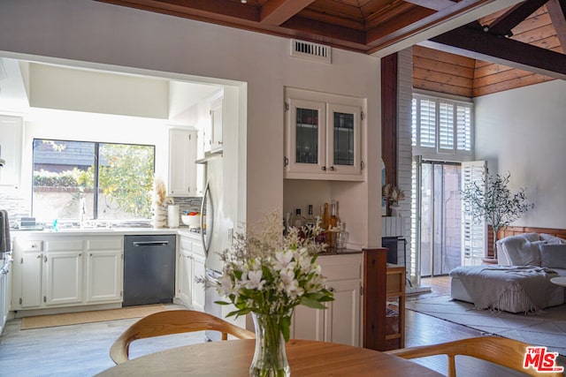 kitchen featuring tasteful backsplash, stainless steel fridge, black dishwasher, beam ceiling, and white cabinets