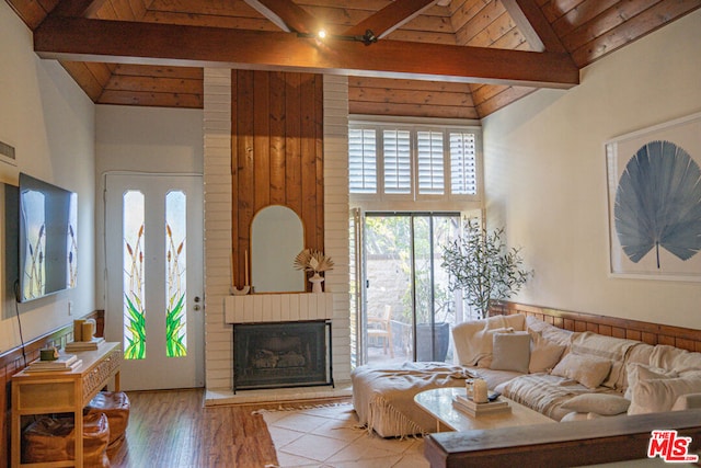 living room featuring wood ceiling, beam ceiling, high vaulted ceiling, wood-type flooring, and a brick fireplace