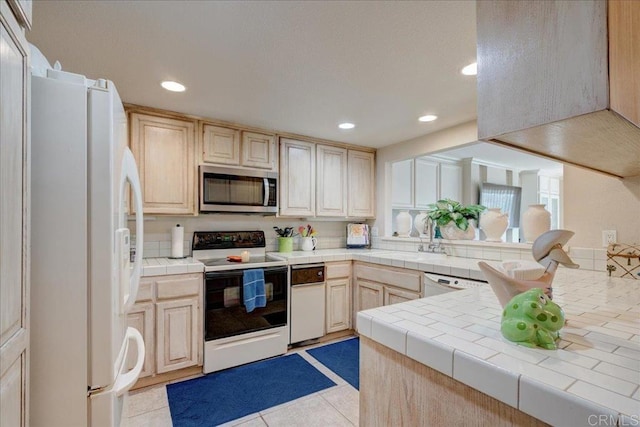 kitchen with sink, tile countertops, white appliances, and light tile patterned floors