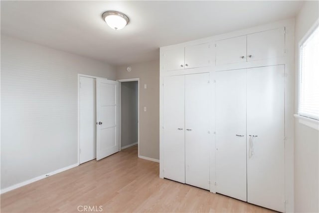 unfurnished bedroom featuring multiple windows, a closet, and light hardwood / wood-style flooring