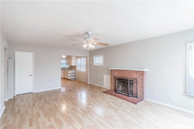 unfurnished living room featuring a brick fireplace, ceiling fan, and light hardwood / wood-style flooring