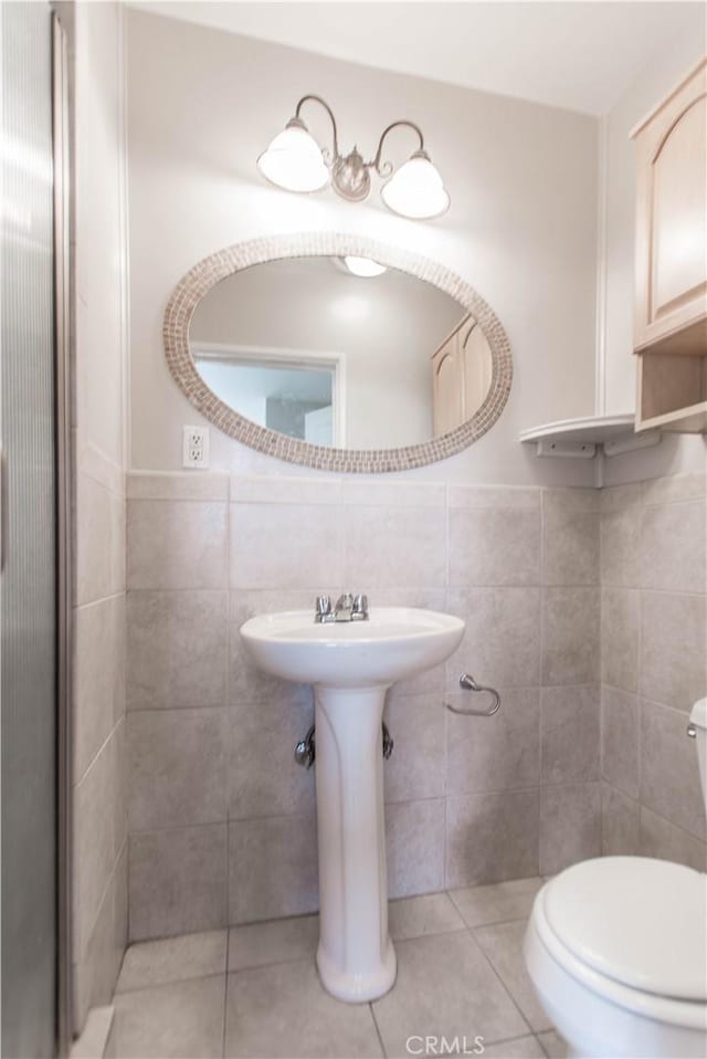 bathroom with tile walls, tile patterned floors, and toilet