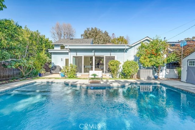 view of pool with cooling unit and a shed