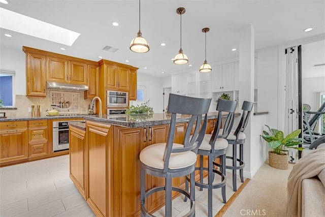 kitchen featuring pendant lighting, a center island, oven, and a kitchen bar