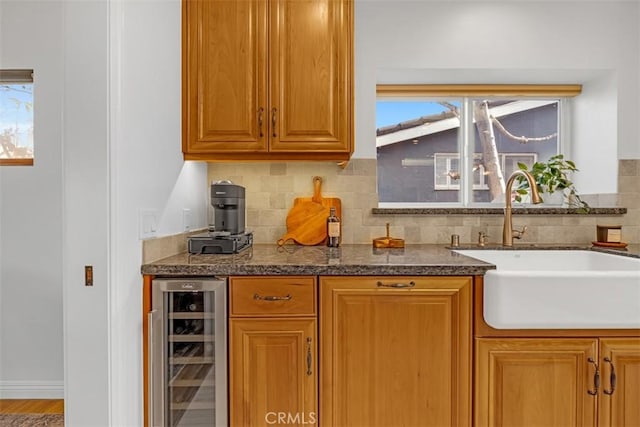 kitchen featuring a healthy amount of sunlight, sink, beverage cooler, and backsplash