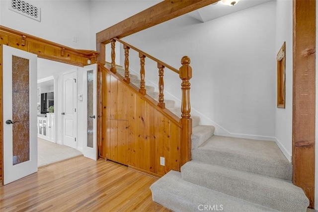 stairway with hardwood / wood-style floors and a high ceiling