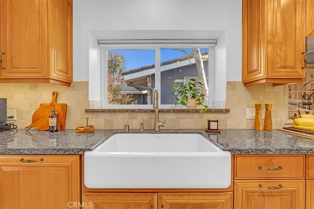 kitchen with dark stone counters, sink, and decorative backsplash