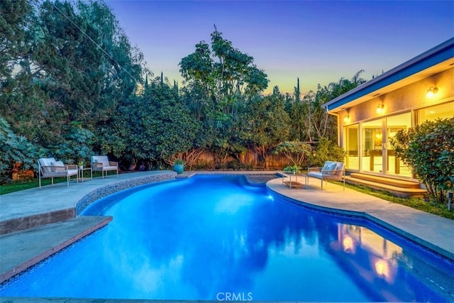 pool at dusk with a patio area