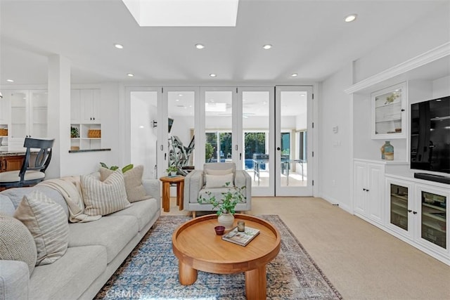 living room with light carpet, a skylight, and french doors