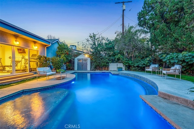 pool at dusk with a patio and a storage unit