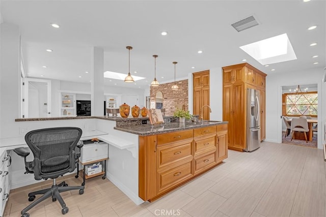 kitchen with pendant lighting, a skylight, a breakfast bar area, dark stone counters, and stainless steel refrigerator with ice dispenser