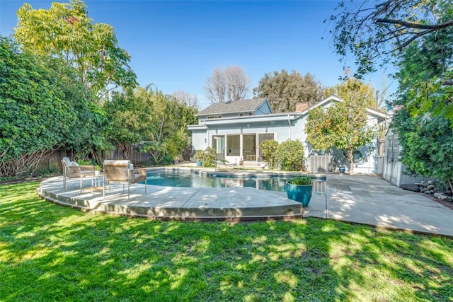 back of house featuring a fenced in pool, a yard, and a patio area