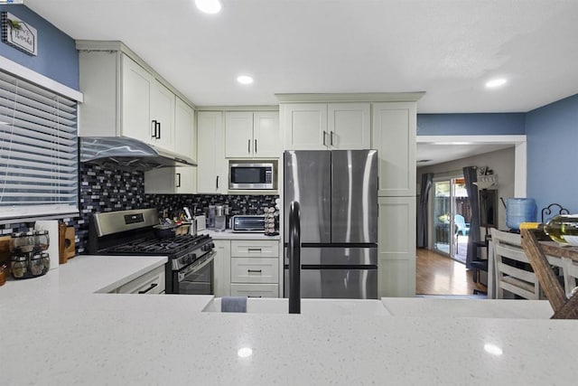 kitchen with tasteful backsplash, light stone countertops, appliances with stainless steel finishes, and white cabinetry