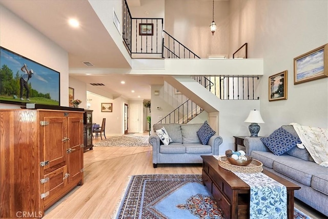 living room with light hardwood / wood-style floors and a high ceiling