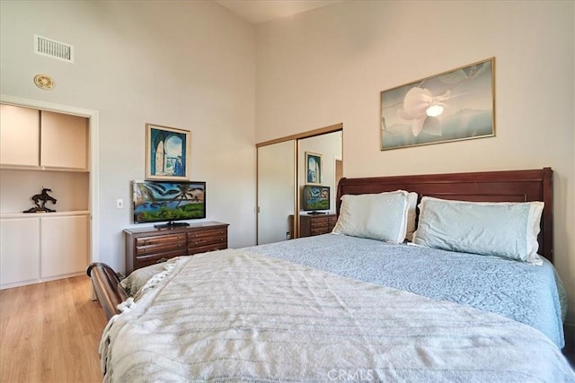 bedroom featuring a high ceiling and light wood-type flooring