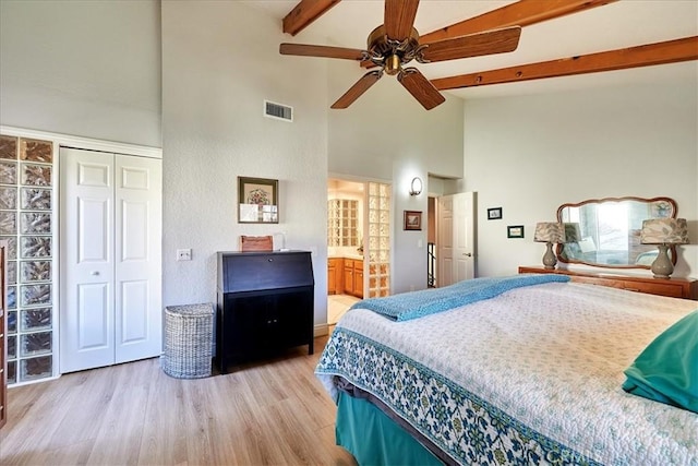 bedroom featuring high vaulted ceiling, a closet, beamed ceiling, ceiling fan, and light hardwood / wood-style floors