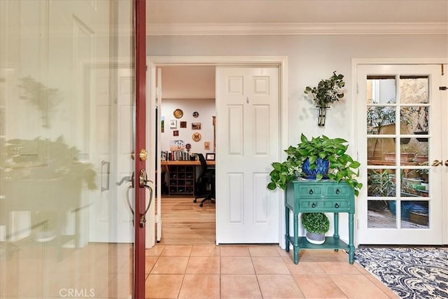 doorway to outside featuring french doors, ornamental molding, and light tile patterned floors