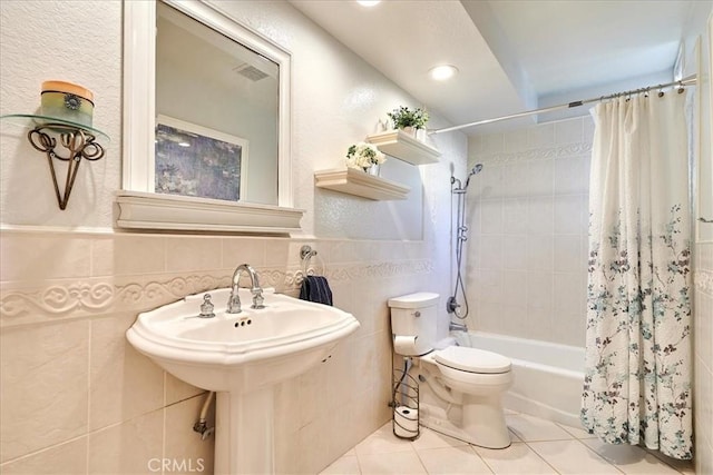 bathroom with toilet, tile walls, tile patterned floors, and shower / tub combo with curtain