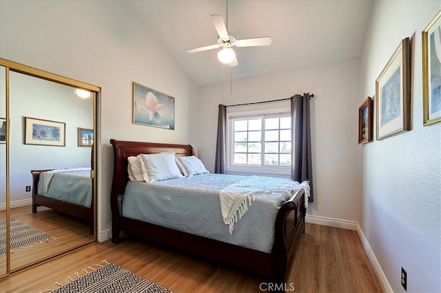 bedroom with ceiling fan, wood-type flooring, vaulted ceiling, and a closet