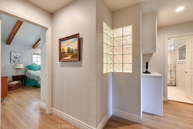 hallway featuring light hardwood / wood-style floors and beamed ceiling