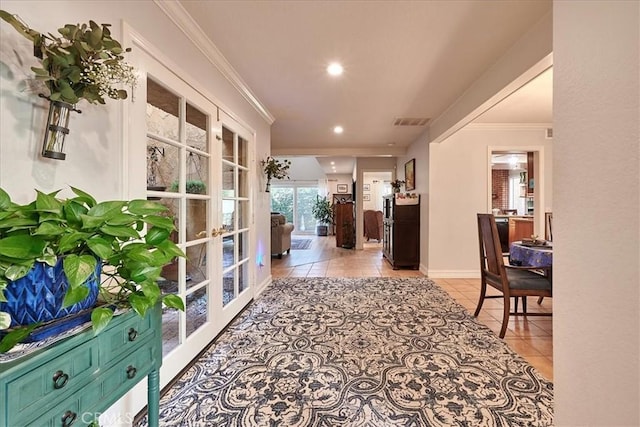 hall featuring light tile patterned floors, ornamental molding, and french doors