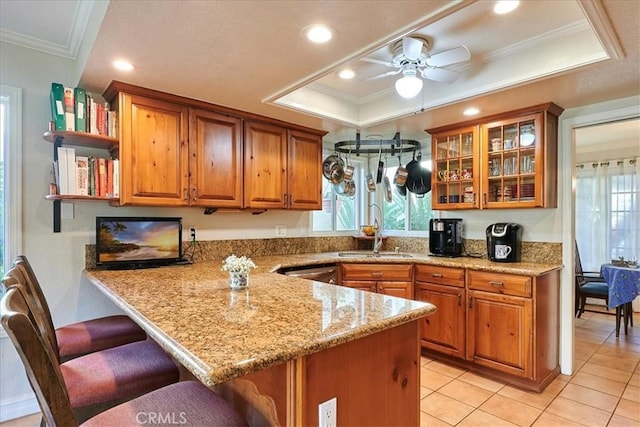 kitchen featuring a tray ceiling, kitchen peninsula, sink, and a breakfast bar area